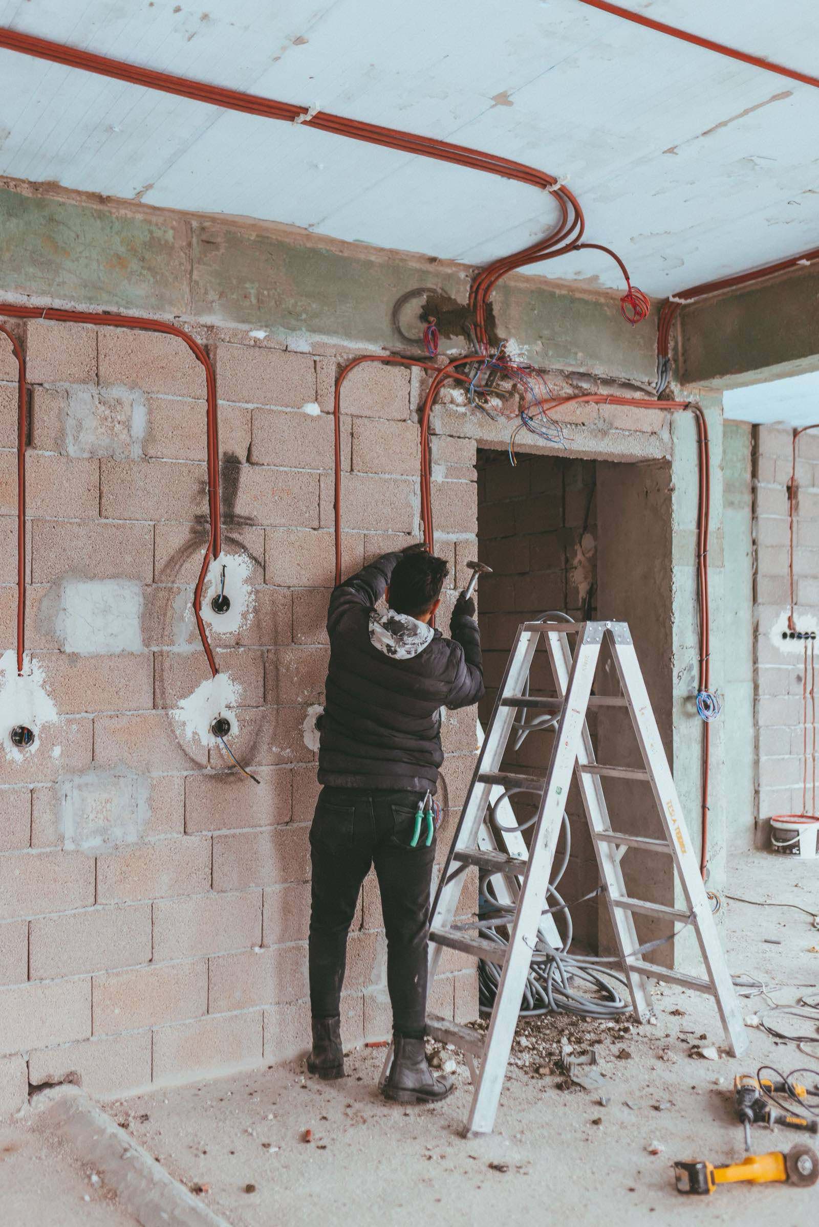 Een elektricien trekt leidingen in een renovatie